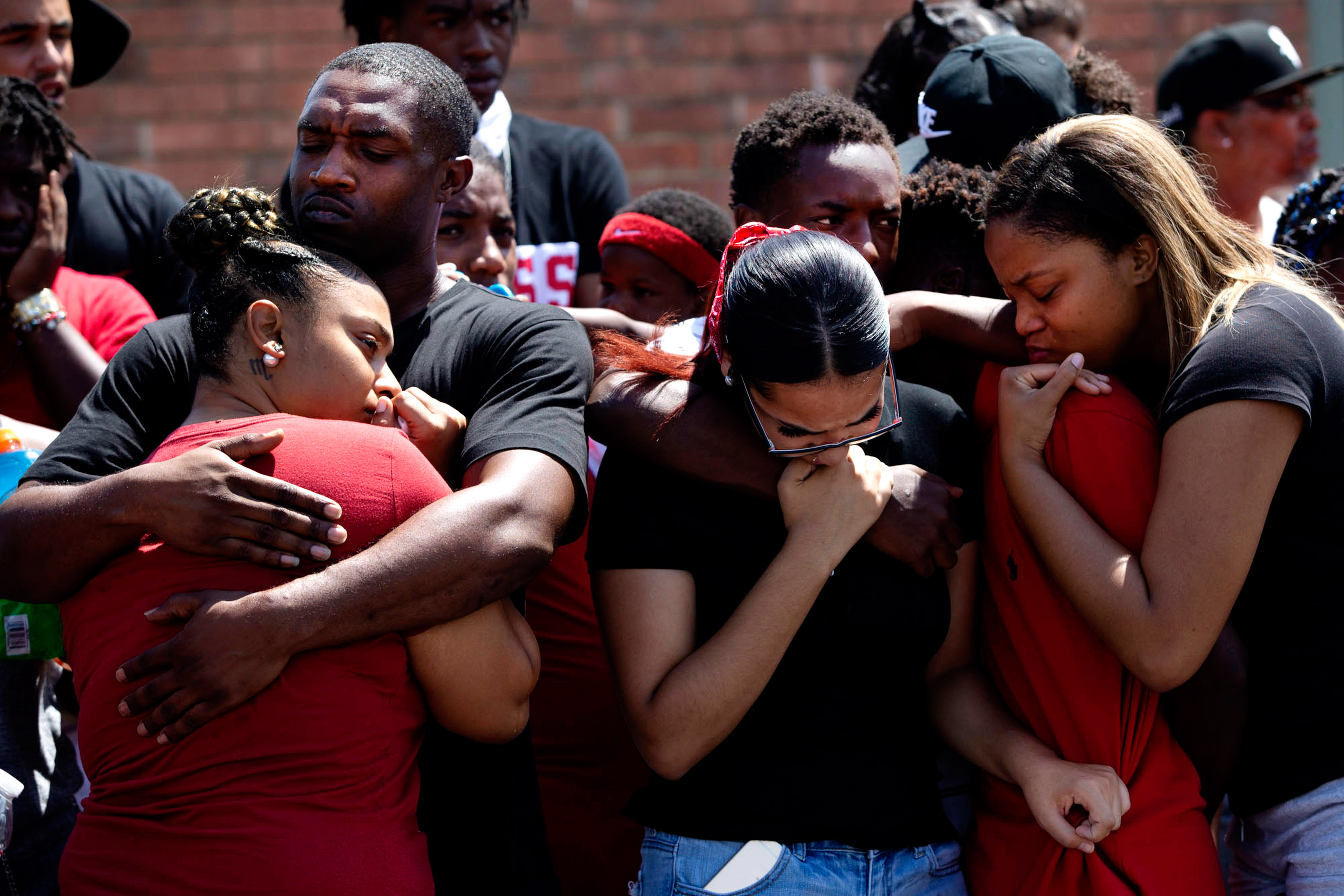 A group of people hold each other in mourning.