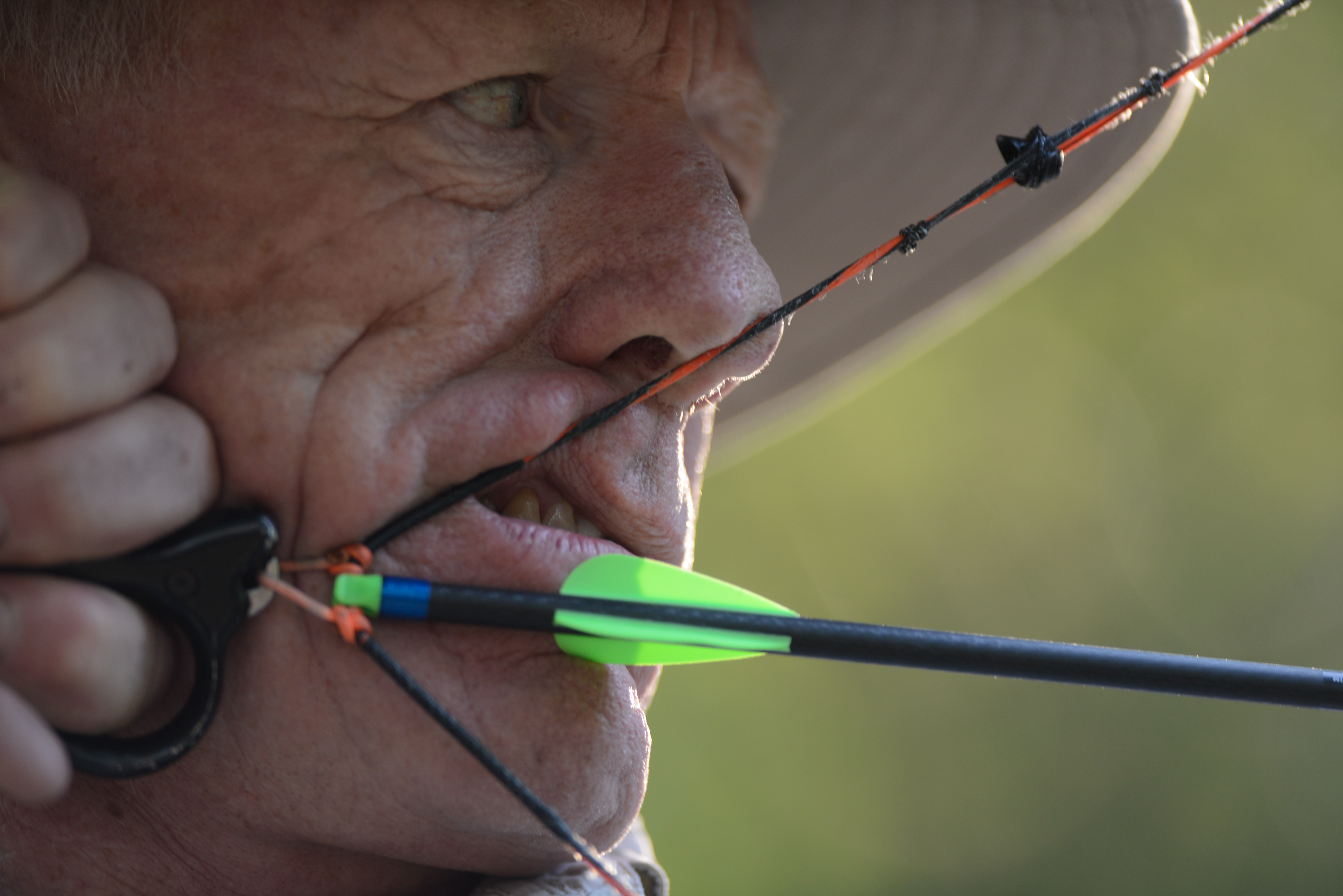 Close up photo of a person taking aim as they draw back an arrow.