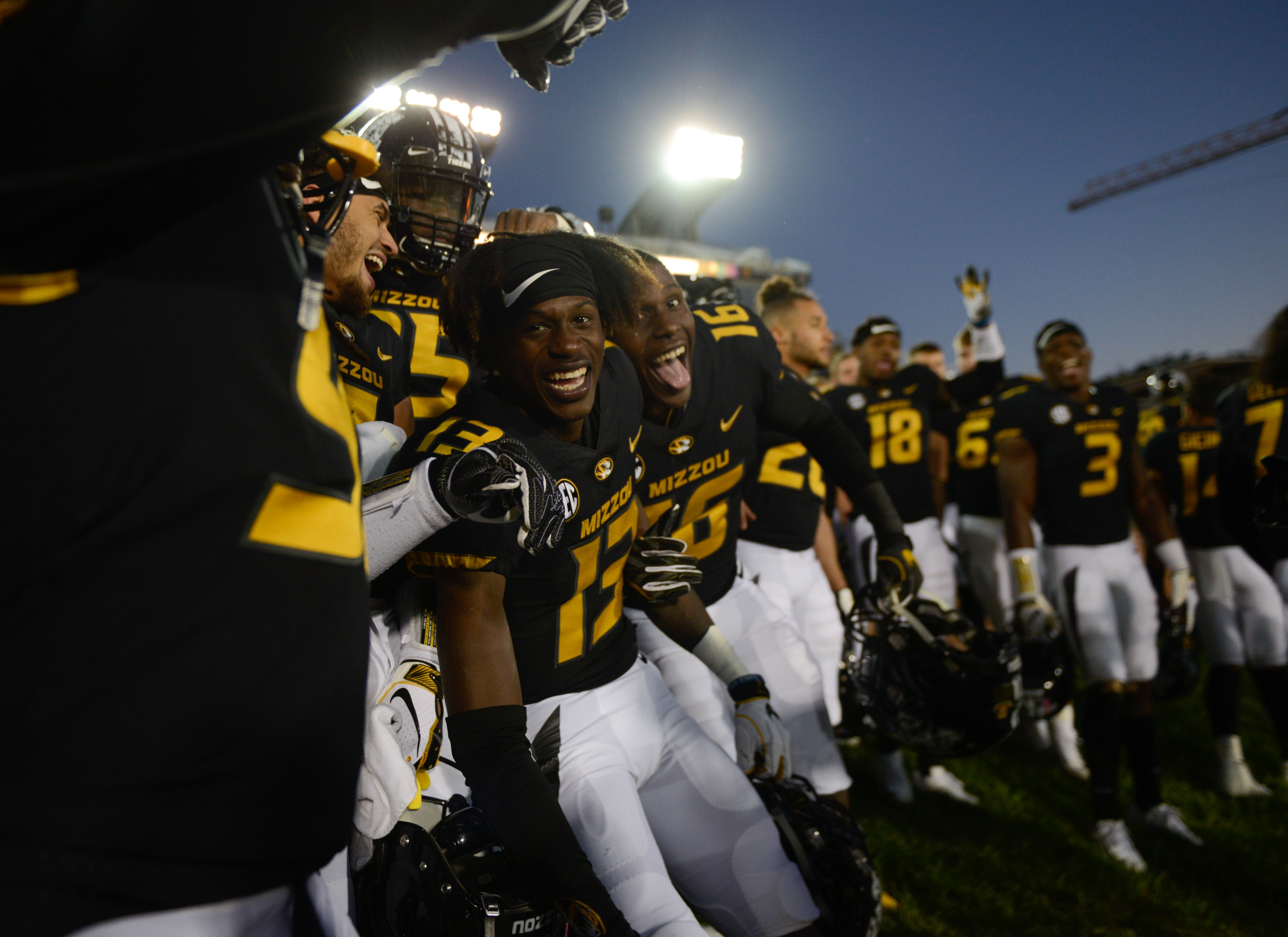 Mizzou football players stand together in celebration after a win.