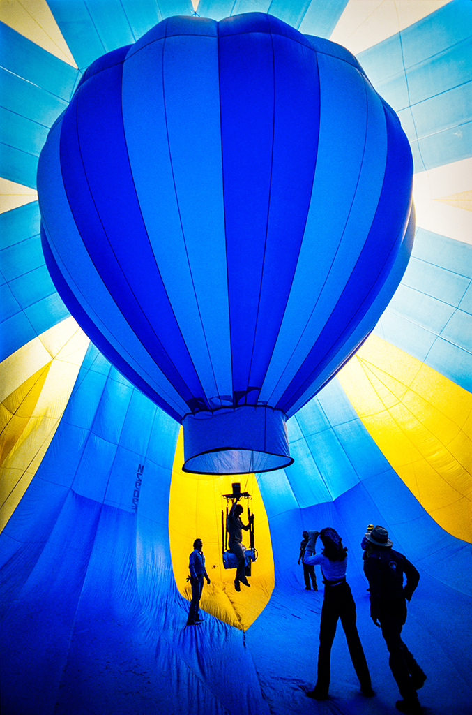 A group of people stand inside what looks like a large air ballon with another air pillow inside it.