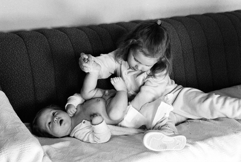 A young child changes the diaper of their infant sibling.