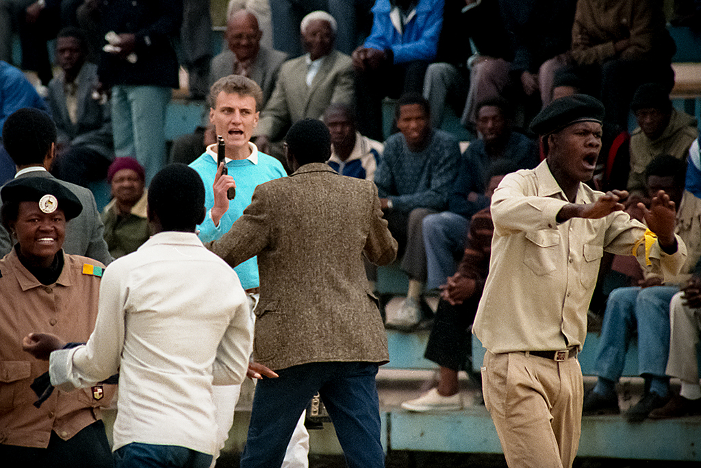 A man holds a pistol among a group of people.