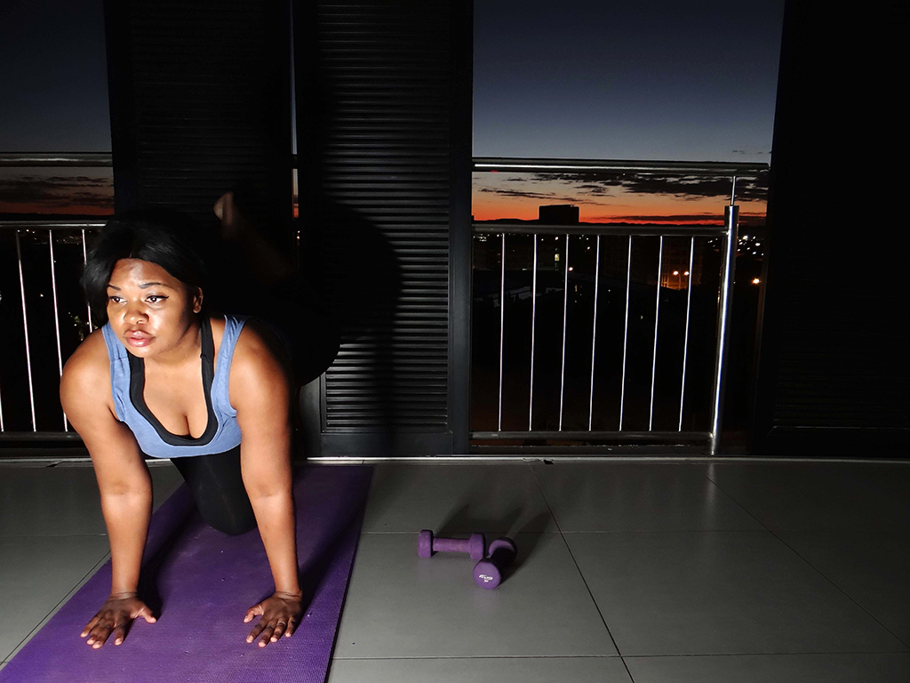 A woman performs an exercise  on a yoga mat.
