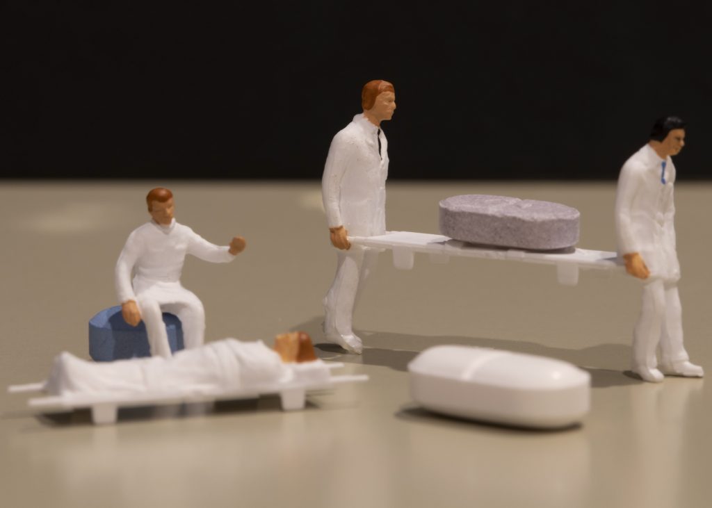 Small figurines positioned around pills of medicine.