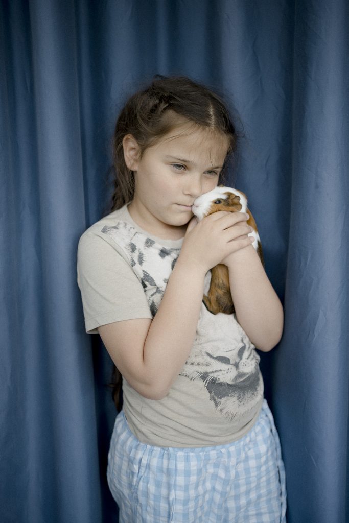 A child holds a guinea pig up to her face.