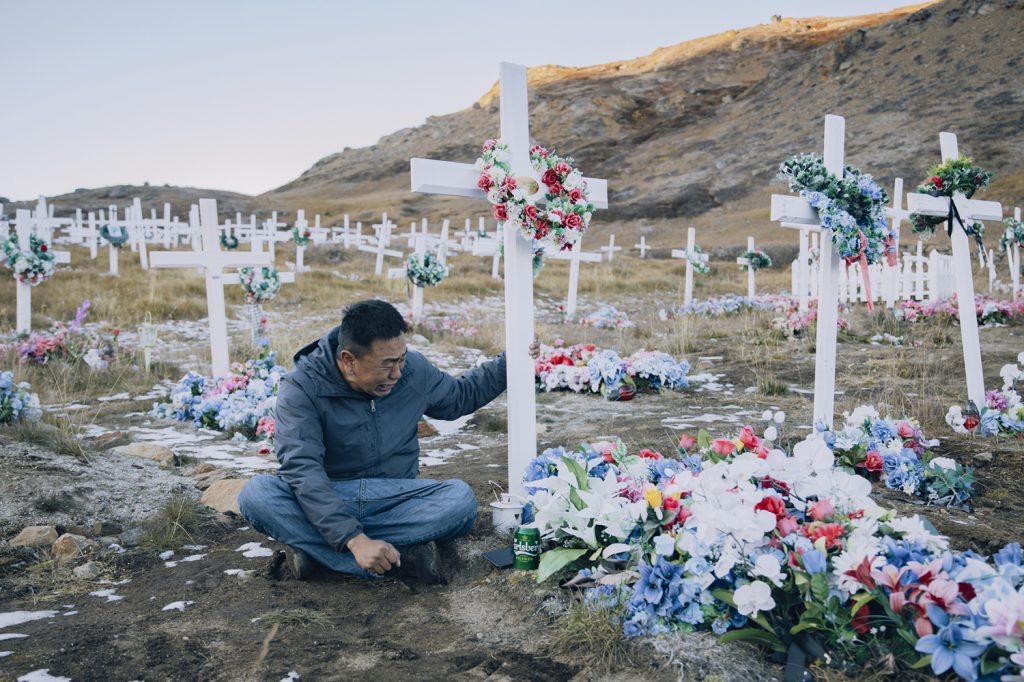 A man cries while sitting next to a grave.