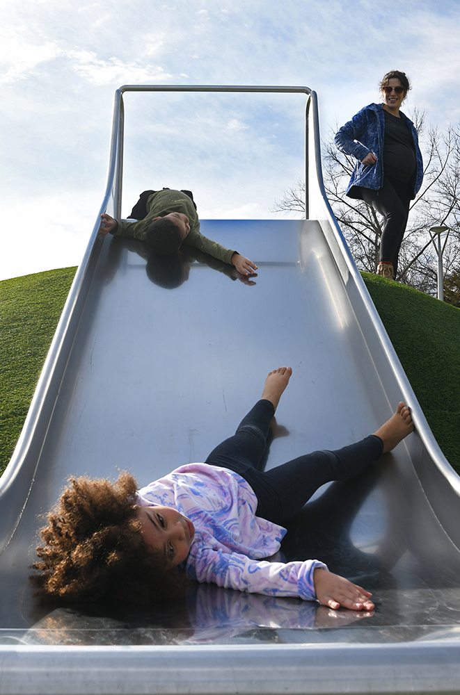 Woman watching children go down a slide