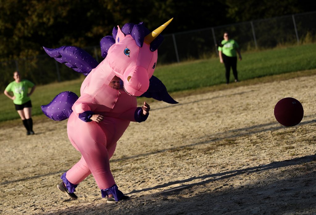 Person in a unicorn costume kicking a ball.