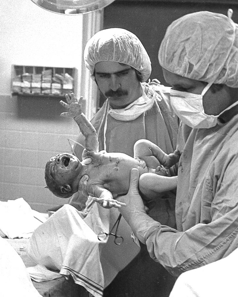 Doctors delivering a newborn infant.