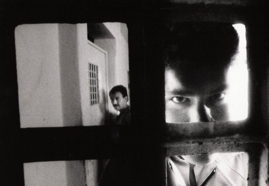 Man looking through bars in prison window.