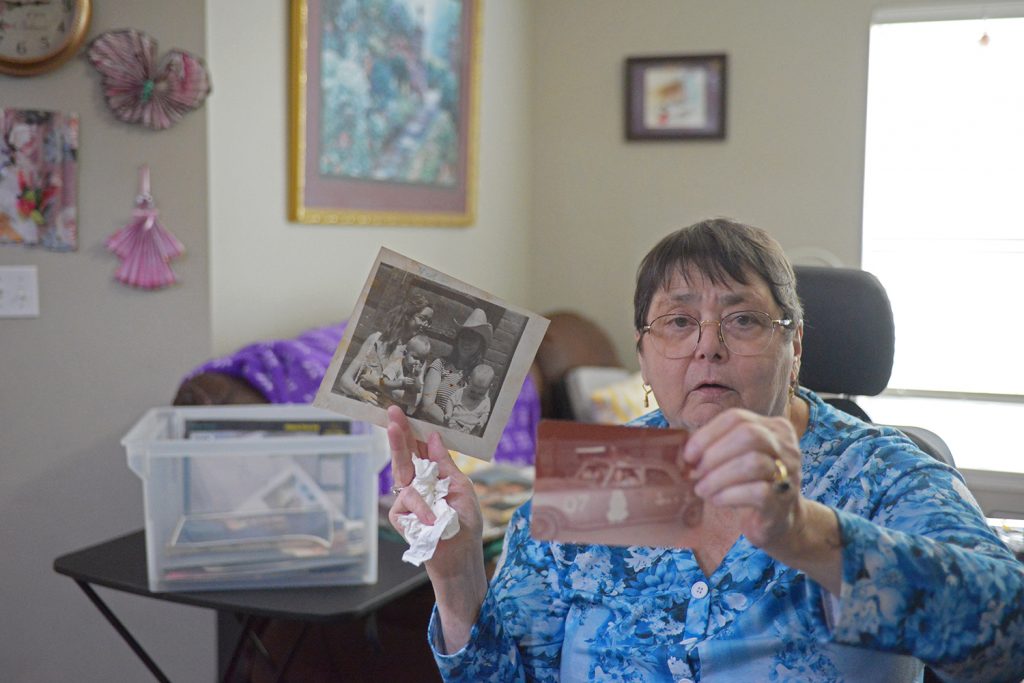 Photograph of a woman holding up photographs in a home