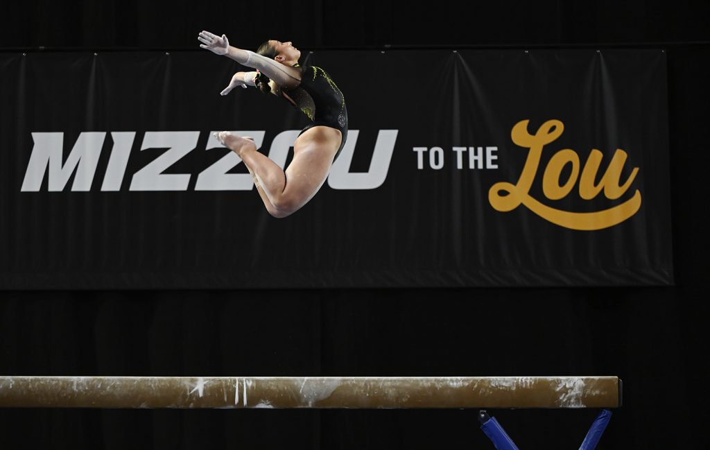 Photograph of female gymnast performing routine on balance beam