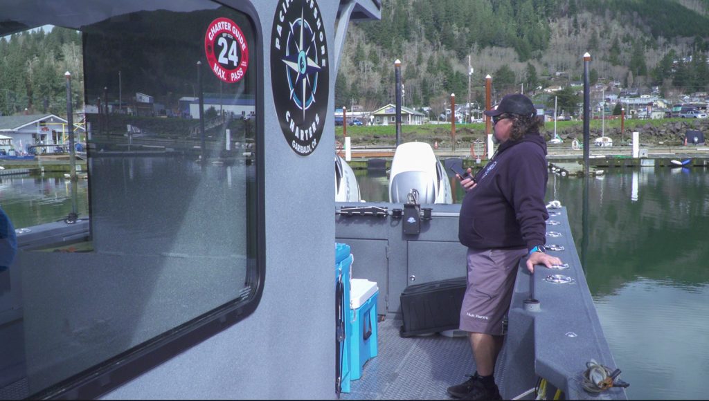 Photograph of a man wearing a sweatshirt and shorts on a boat