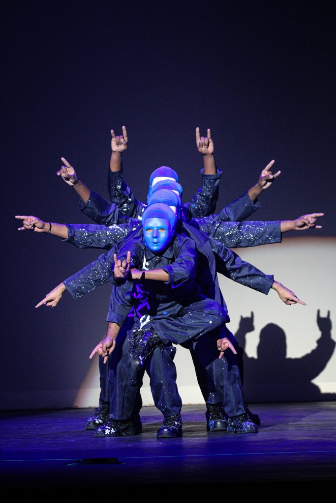 Photograph of performers wearing blue masks and clothes