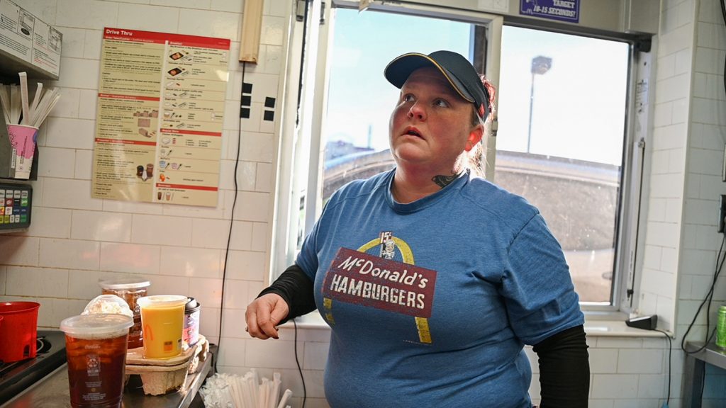 Photograph of a woman working at a drive through window of a McDonalds restaurant