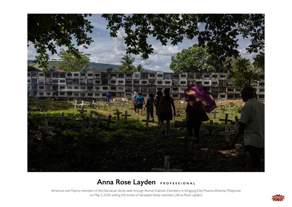 Photograph of a group of people walking through a cemetery in the Philippines.