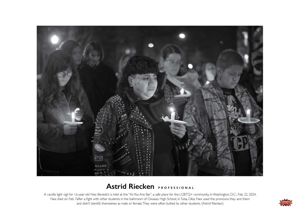 Photograph of people outside holding candles at a vigil.