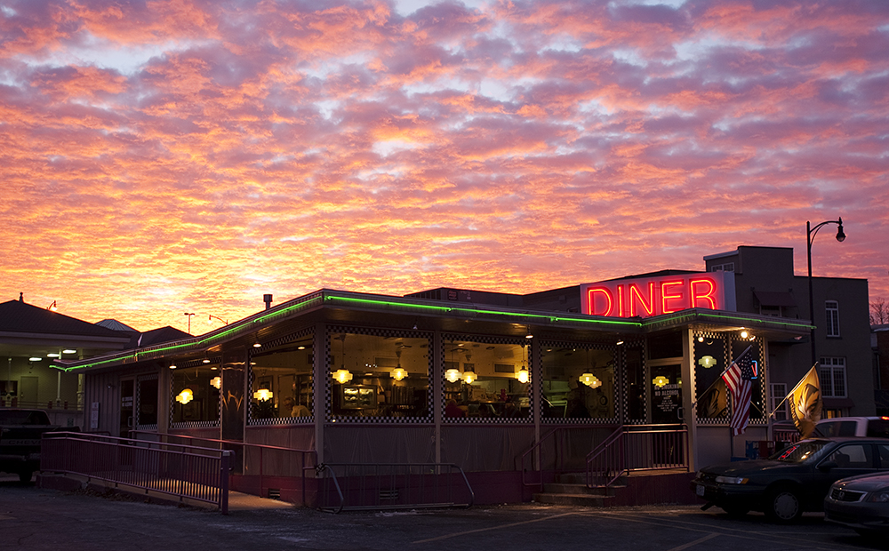Photograph of a diner with a cloudy pink sky at sunrise.