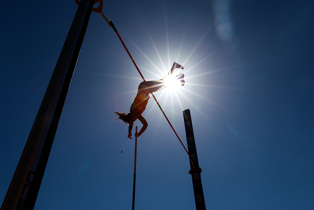 Silhouetted pole vaulter clearing the bar